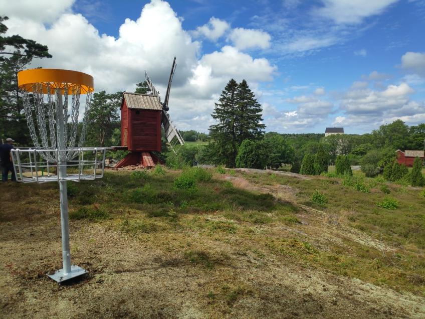 Discgolfkorg med väderkvarn och Kastelholms slott i bakgrunden